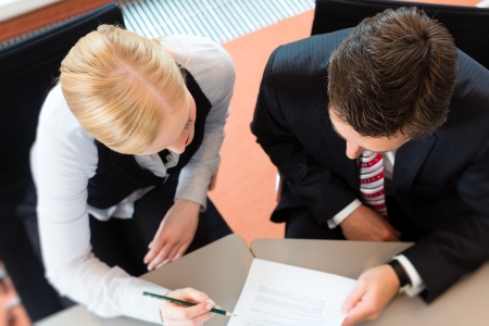 Businesspeople sitting at office desk with a document and laptopの写真素材