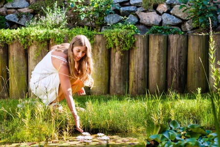 Woman sitting at pond in her garden on a bright summer dayの写真素材