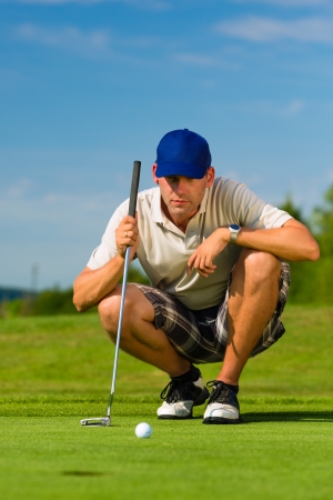Young golf player on course putting, he aiming for his put shotの写真素材
