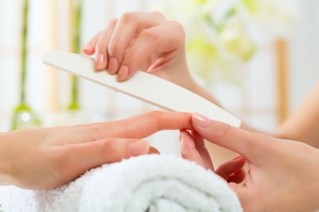Woman in a nail salon receiving a manicure by a beauticianの写真素材