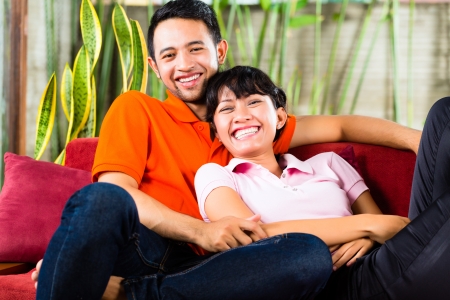 Indonesian couple sitting cozy at home on the sofa and relaxingの写真素材