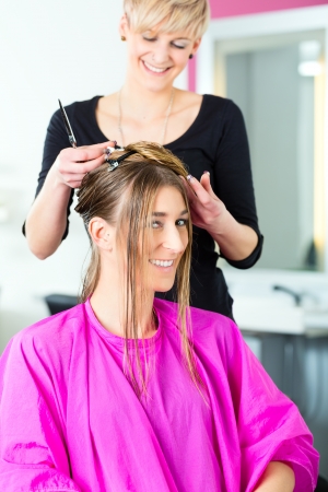 Hairdresser - hair stylist cutting hair, a female customer gets a haircutの写真素材