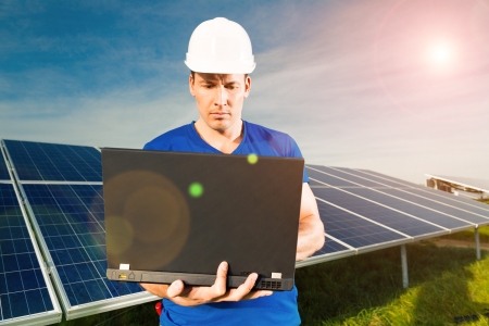 Photovoltaic system with solar panels for the production of renewable energy through solar energy, a technician standing in front with a laptopの写真素材