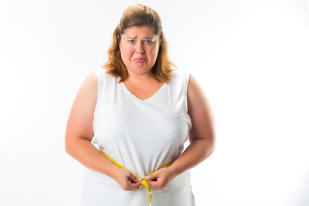 obese woman measuring her waist with tape and is unhappyの写真素材