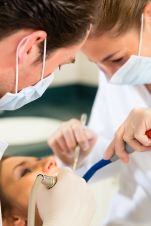 Female patient with dentist and assistant in a dental treatment, wearing masks and glovesの写真素材
