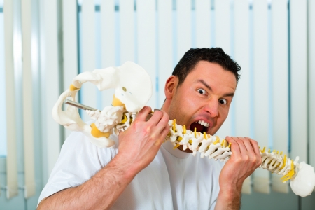 Portrait of a crazy therapist in his practice, he bites in a backbone or spineの写真素材