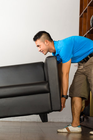Real estate market - Young Indonesian man lifting a sofa put it awayの写真素材