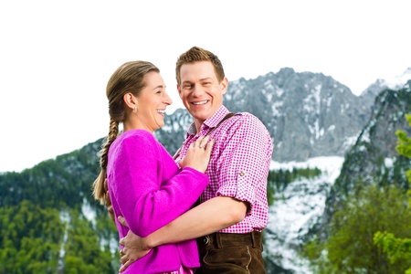 Happy Couple in traditional dress is standing in the meadow with mountain panoramaの写真素材