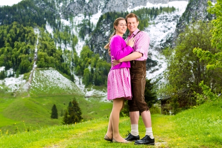 Happy Couple in traditional dress is standing in the meadow with mountain panoramaの写真素材