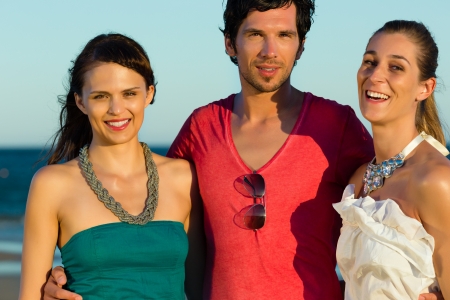 Man and two women enjoy the romantic sunsetの写真素材