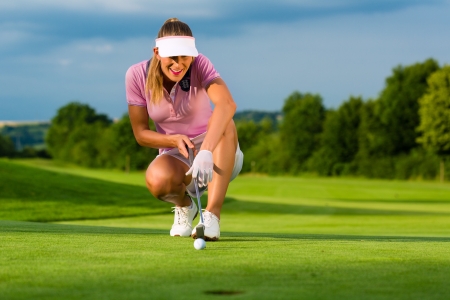 Young female golf player on course aiming for putの写真素材