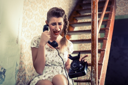 Woman sitting on the stairs and crying on the phoneの写真素材