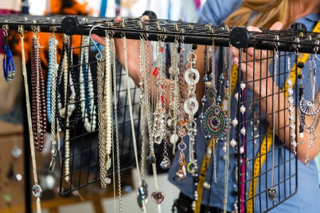 Freelance - jewelry designer working on a draft, different pieces of jewelry hanging in frontの写真素材