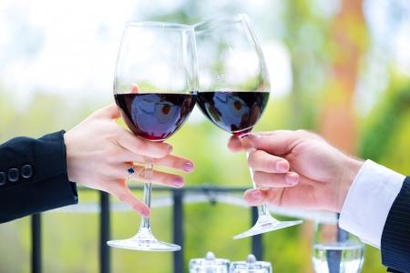 Clink with red wine glasses outside on the terrace in a fine dining restaurantの写真素材