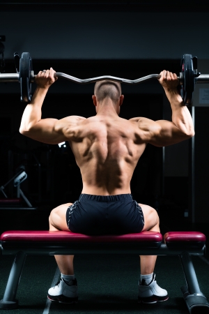 Strong man - bodybuilder with dumbbells in a gym, exercising with a dumbbellの写真素材