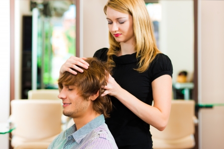 Man at the hairdresser, she is cutting his hairの写真素材