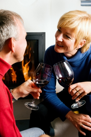 Mature couple having fun clinking glasses with red wine in a romantic settingの写真素材