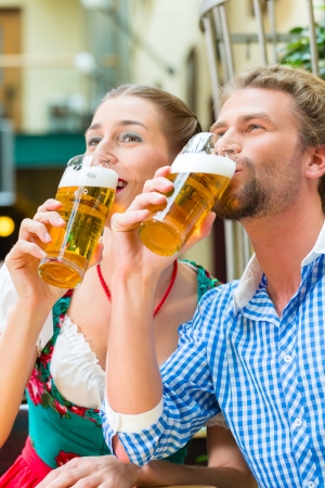Young couple in traditional Bavarian Tracht in restaurant or pub with beerの写真素材