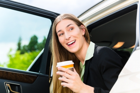 Young businesswoman gets out of taxi, she holding a cup of coffeeの写真素材