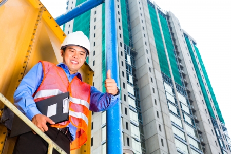 Chinese construction worker or supervisor or architect with clipboard on a building site in Asiaの写真素材
