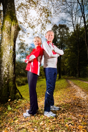 Senior Couple doing sport outdoor and posing on a forest road in the autumnの写真素材