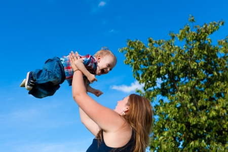 Family - mother and child playing in garden on a beautiful summer dayの写真素材