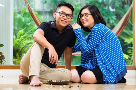 Young Indonesian couple - man and woman - at home playing with marblesの写真素材