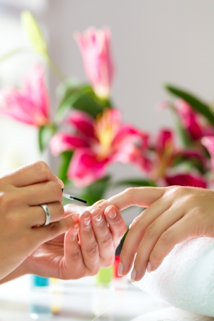 Woman in a nail salon receiving a manicure by a beauticianの写真素材