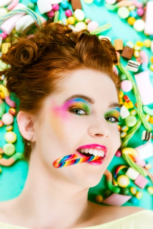Young woman with many unhealthy sweets or candy in Studioの写真素材