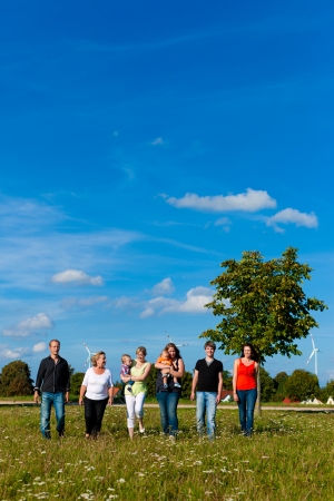 Family and multi-generation - mother, father, children and grandmother having fun on meadow in summerの写真素材