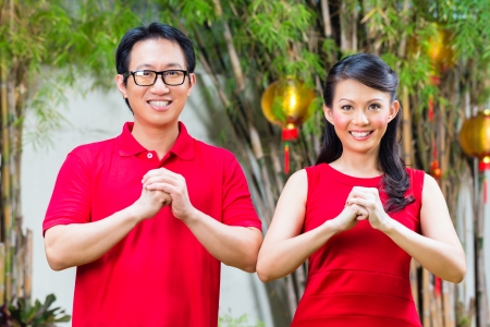 Couple celebrating Chinese new year traditional greeting, wearing redの写真素材