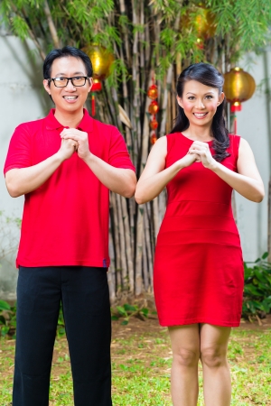 Couple celebrating Chinese new year traditional greeting, wearing redの写真素材