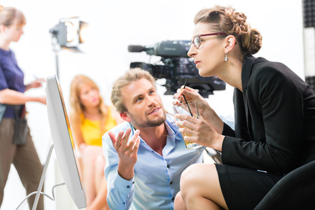 Team or Director discussing during a break the scene direction on set of a commercial video production or reportage at a screenの写真素材