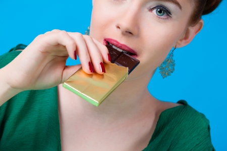 Young woman with chocolate in Studio, she have a sweet tooth and biting in a chocolate bar out of a glassの写真素材
