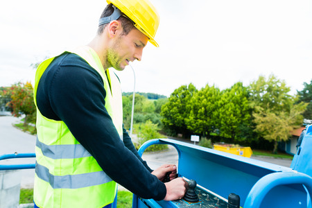 Construction workers or crane driver on site driving hydraulic lifting ramp with control desk