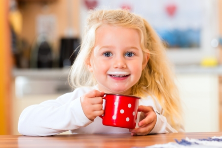 child drinking cup or mug of milk in the domestic kitchen  の写真素材
