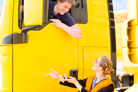 Logistics - proud driver or forwarder in drivers cap of truck and trailer, on a transshipment pointの写真素材