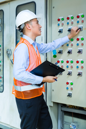 Asian Indonesian Technician or electrician making function test on Panel or switchbox for the control of air conditioners on construction site or in factory for acceptanceの写真素材