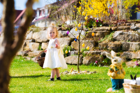 Little Girl on an Easter Egg hunt on a meadow in spring, she holding a basket or Easter basketの写真素材