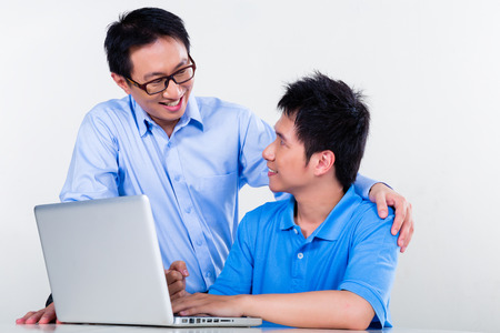 Chinese father helps his son with knowledge and experience for his complex and complicated homework assignments for the next day at schoolの写真素材