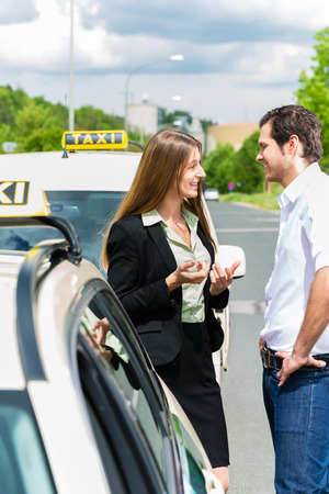 Young woman and driver standing together in front of taxi, she has reached her destinationの写真素材