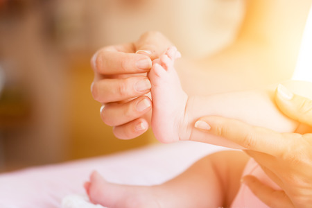 Baby with mother, she is holding her feetの写真素材