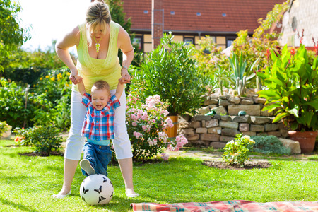 Family - mother and child playing in garden on a beautiful summer dayの写真素材
