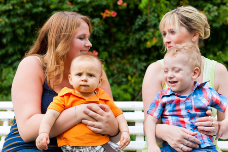 Happy young mother and grandmother sitting with their children and grandchildren in a park outdoors...