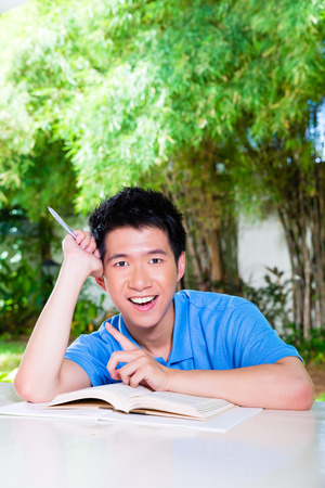 Young Chinese Asian student is successful at home with difficult homework assignment for school next dayの写真素材