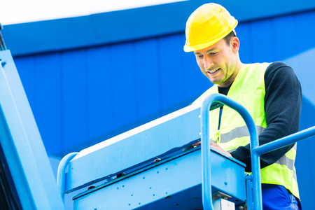 Construction workers or crane driver on site driving hydraulic lifting ramp with control desk