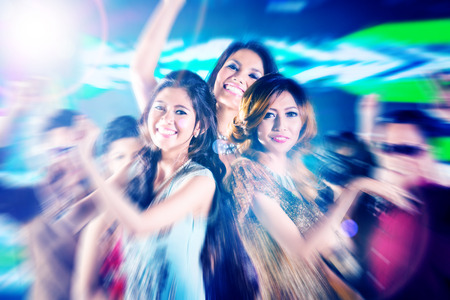 Asian beautiful friends dancing on disco floor having fun at fancy night clubの写真素材