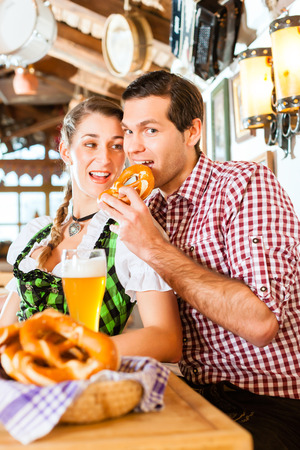 Bavarian couple wearing traditional dress, flirting and  drinking beer in restaurantの写真素材