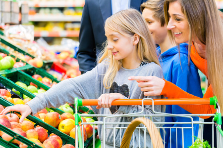 Family in supermarket selecting fruits while grocery shopping の写真素材