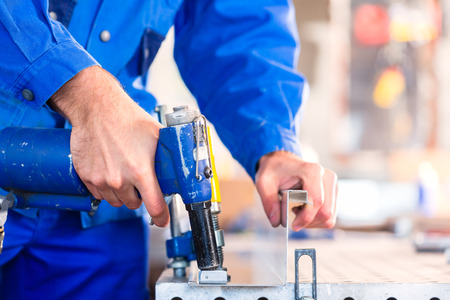Craftsman rivet metal with air compressed pistol in workshopの写真素材